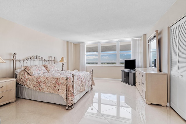 bedroom featuring a closet, a textured ceiling, and light tile patterned floors