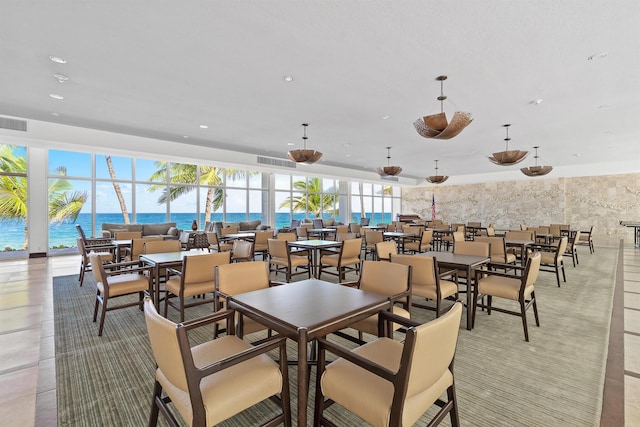 dining space featuring a water view and light tile patterned floors