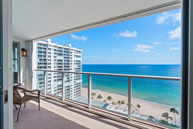 balcony featuring a view of the beach and a water view