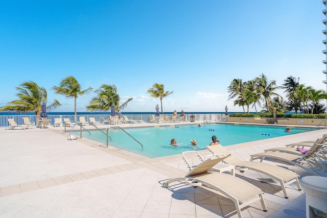 view of pool with a patio and a water view