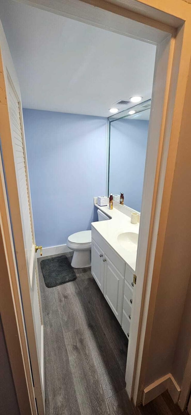 bathroom featuring wood-type flooring, toilet, and vanity