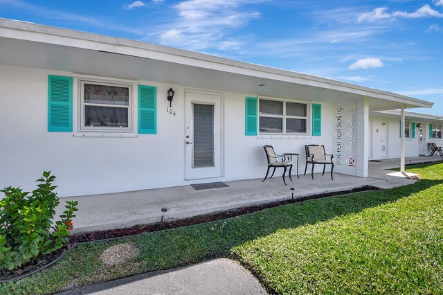 view of exterior entry featuring a yard and covered porch