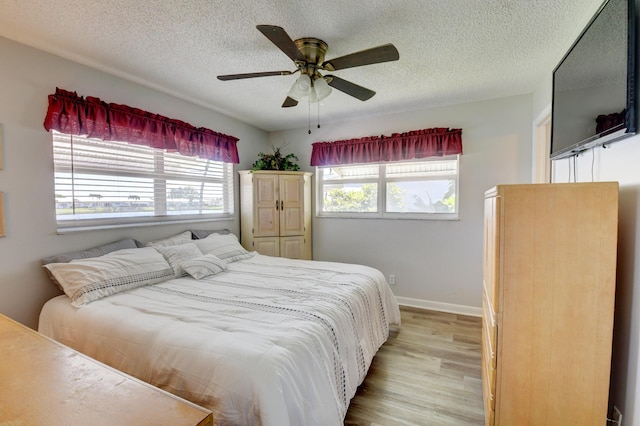 bedroom with ceiling fan, light hardwood / wood-style flooring, and a textured ceiling