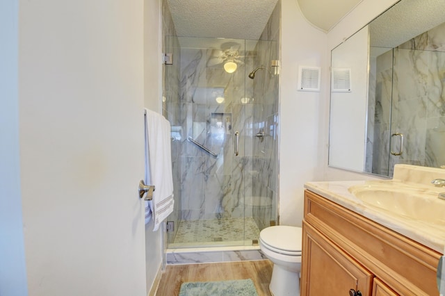 bathroom featuring hardwood / wood-style flooring, vanity, toilet, a shower with door, and a textured ceiling