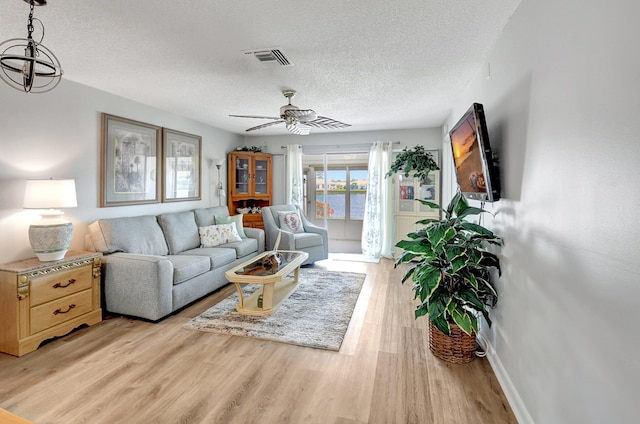 living room featuring ceiling fan, a textured ceiling, and light hardwood / wood-style flooring