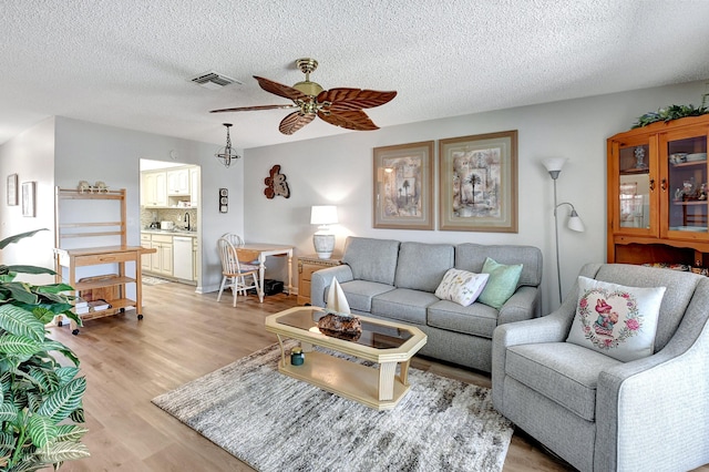 living room featuring a textured ceiling, light hardwood / wood-style flooring, and ceiling fan