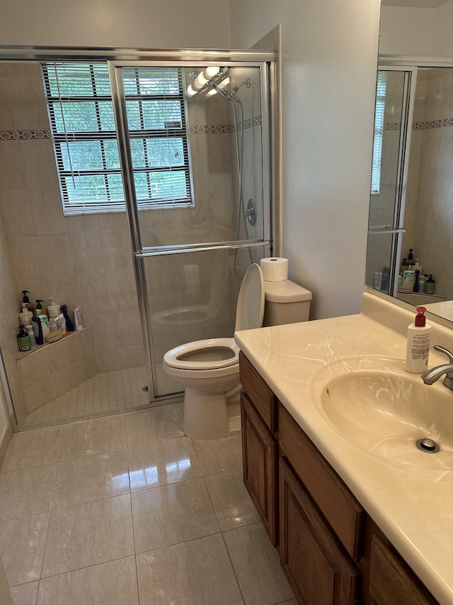 bathroom with vanity, tile patterned floors, a shower with door, and toilet