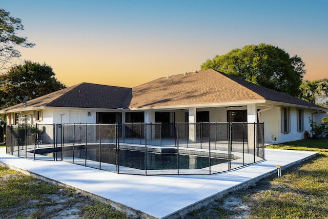 back house at dusk with a fenced in pool, a patio, and ceiling fan