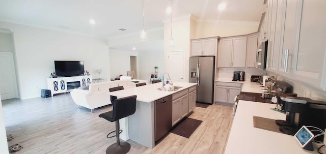 kitchen featuring a breakfast bar area, hanging light fixtures, a kitchen island with sink, stainless steel appliances, and light hardwood / wood-style flooring