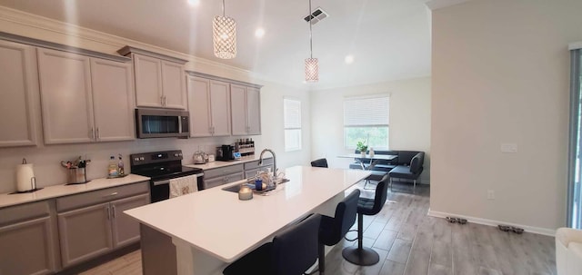 kitchen with pendant lighting, sink, a center island with sink, light wood-type flooring, and black / electric stove