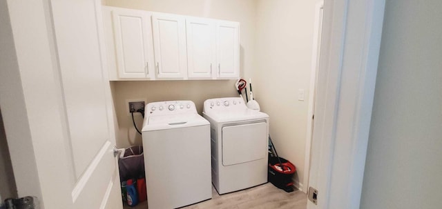 clothes washing area featuring cabinets and separate washer and dryer