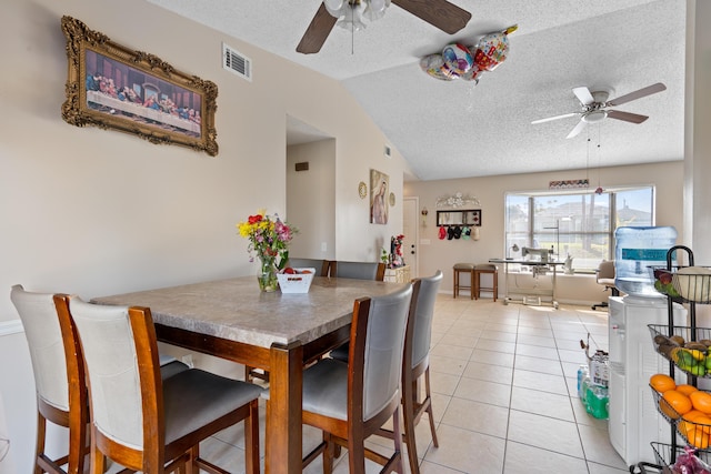 tiled dining area with ceiling fan, lofted ceiling, and a textured ceiling