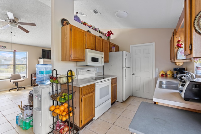 kitchen with light tile patterned flooring, vaulted ceiling, a textured ceiling, ceiling fan, and white appliances