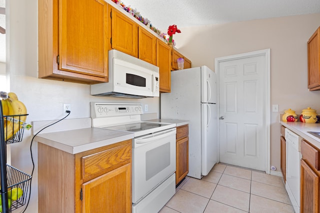 kitchen featuring light tile patterned flooring, a textured ceiling, and white appliances