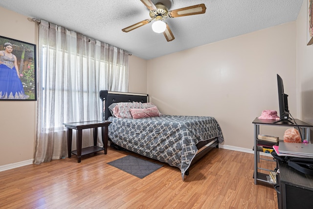 bedroom featuring ceiling fan, a textured ceiling, and light hardwood / wood-style floors