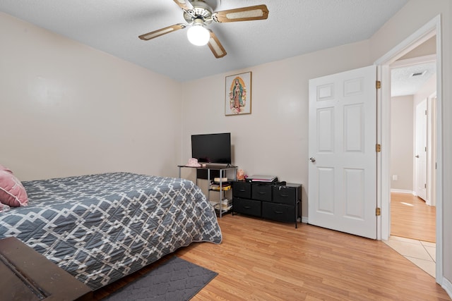 bedroom with ceiling fan, a textured ceiling, and light hardwood / wood-style flooring