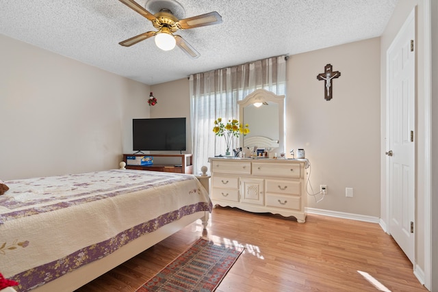 bedroom with ceiling fan, a textured ceiling, and light wood-type flooring