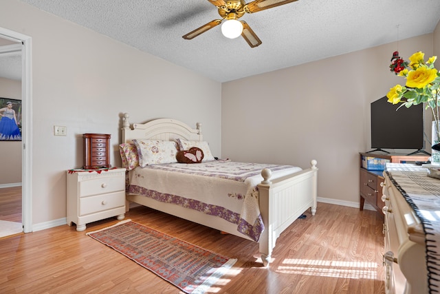 bedroom with ceiling fan, light hardwood / wood-style floors, and a textured ceiling