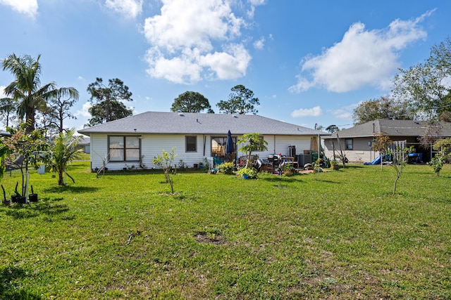 rear view of property with central AC, a yard, and a playground