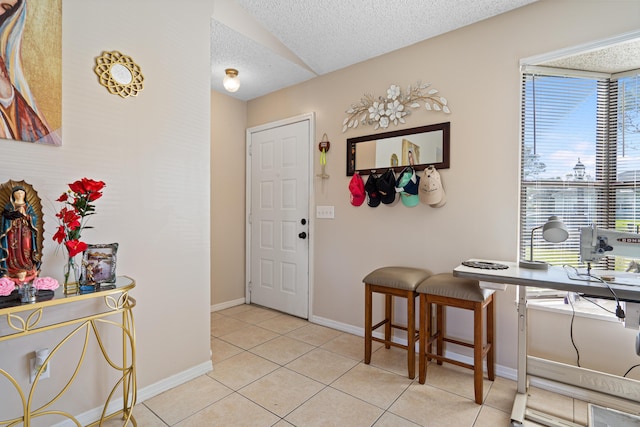 tiled entryway with a textured ceiling and a healthy amount of sunlight