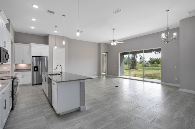 kitchen with pendant lighting, sink, black appliances, white cabinets, and a center island with sink