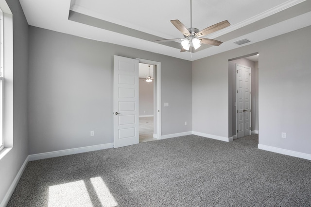 carpeted empty room with ceiling fan and a raised ceiling