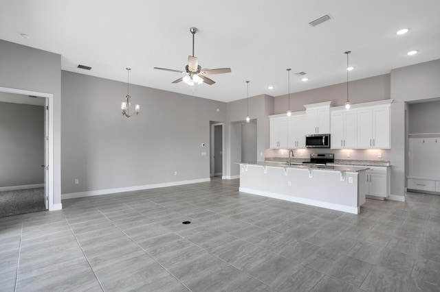 kitchen with a kitchen bar, sink, white cabinetry, a center island with sink, and stainless steel appliances