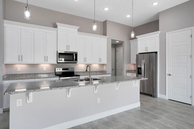 kitchen with sink, appliances with stainless steel finishes, a kitchen island with sink, hanging light fixtures, and white cabinets