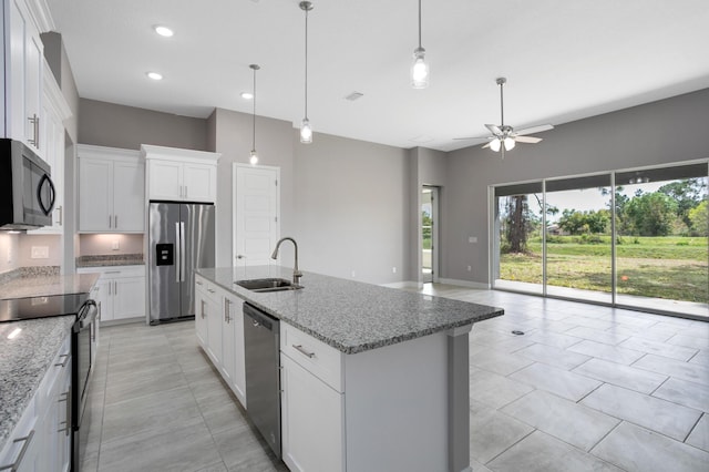 kitchen featuring sink, white cabinetry, appliances with stainless steel finishes, light stone countertops, and a kitchen island with sink