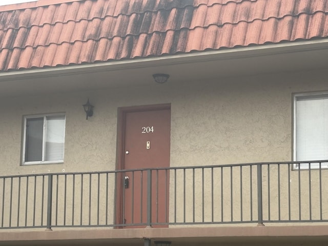 property entrance with stucco siding and a tiled roof