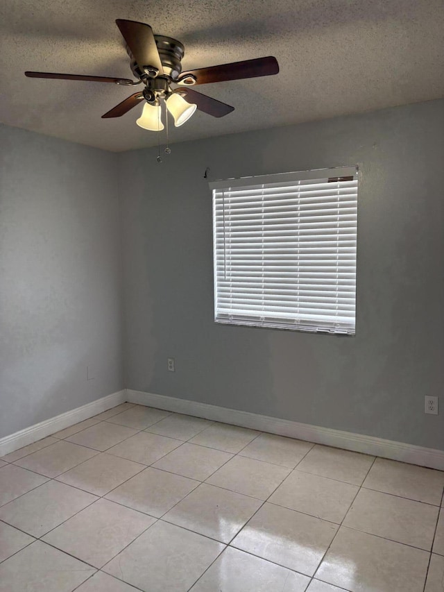 unfurnished room featuring light tile patterned floors, a ceiling fan, baseboards, and a textured ceiling