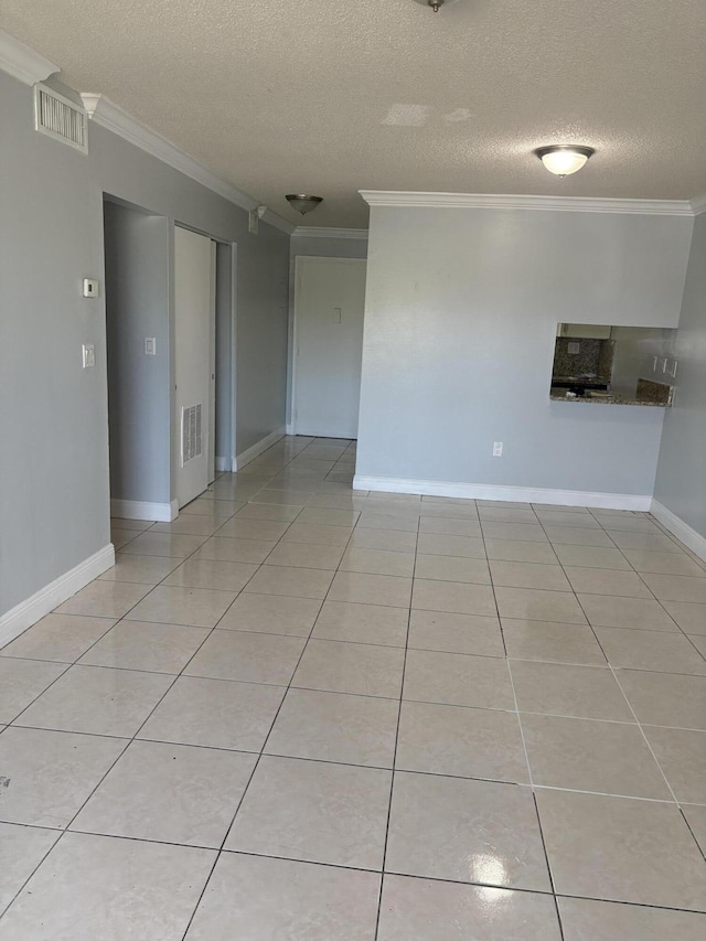 empty room with visible vents, a textured ceiling, light tile patterned flooring, and crown molding