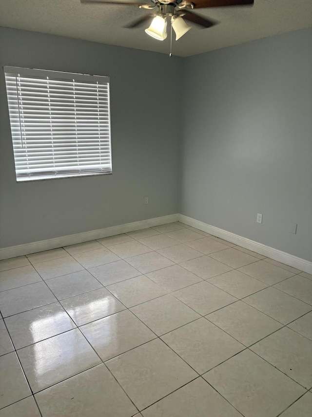 spare room with light tile patterned floors, baseboards, and ceiling fan