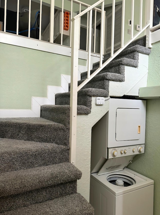 stairway with stacked washer and dryer and a textured wall