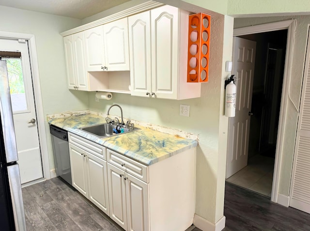 kitchen with white cabinets, dark wood finished floors, stainless steel appliances, light countertops, and a sink