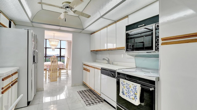 kitchen with sink, white appliances, hanging light fixtures, and white cabinets