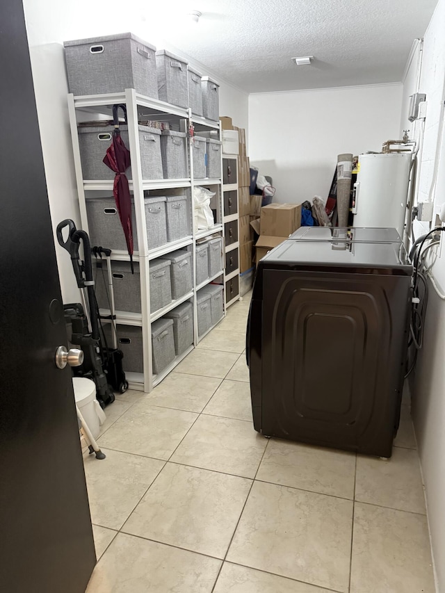 laundry area with light tile patterned floors, washing machine and clothes dryer, electric water heater, and a textured ceiling