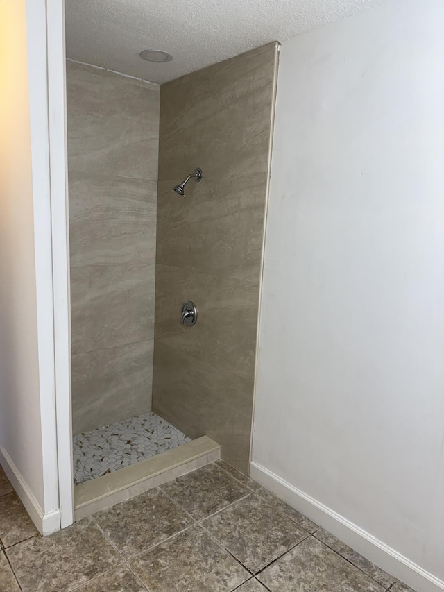 bathroom featuring a tile shower, tile patterned floors, and a textured ceiling