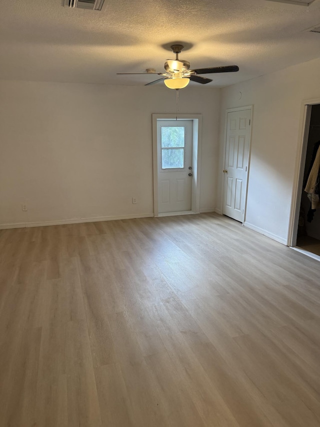 spare room with ceiling fan, a textured ceiling, and light wood-type flooring