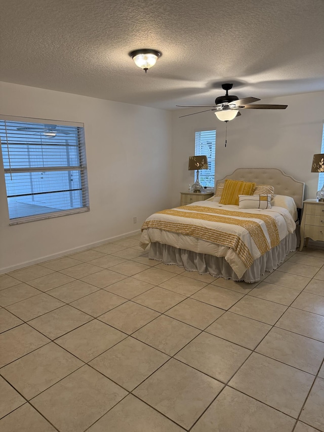 unfurnished bedroom with ceiling fan, light tile patterned floors, multiple windows, and a textured ceiling