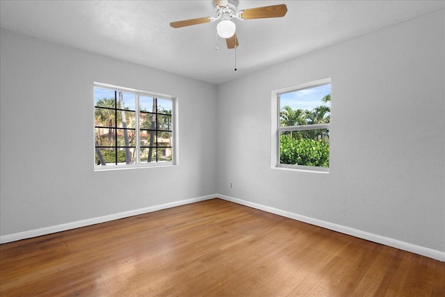 unfurnished room featuring a healthy amount of sunlight, hardwood / wood-style floors, and ceiling fan