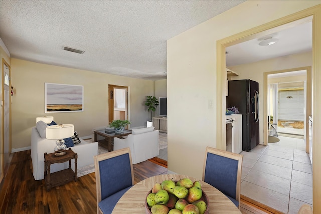 dining room with wood-type flooring and a textured ceiling