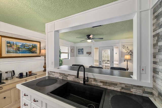 kitchen with white cabinetry, ceiling fan, sink, and a textured ceiling