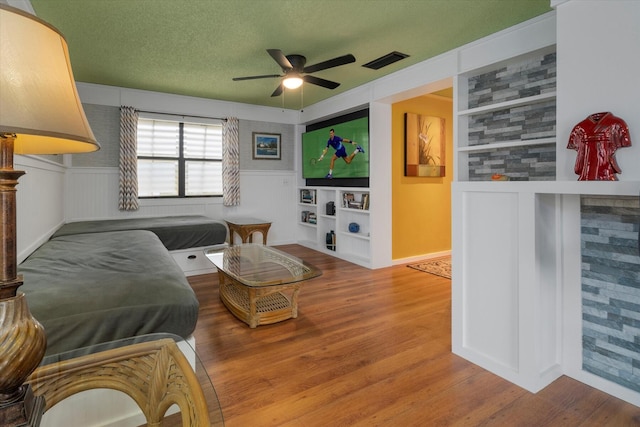 living room featuring ceiling fan, wood-type flooring, and a textured ceiling