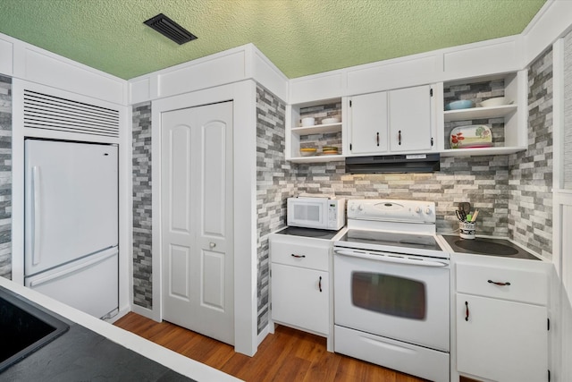 kitchen featuring hardwood / wood-style floors, white cabinets, decorative backsplash, white appliances, and a textured ceiling