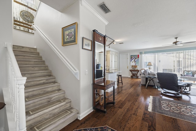 stairway featuring hardwood / wood-style flooring, ceiling fan, and a textured ceiling