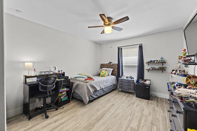 bedroom with ceiling fan, light hardwood / wood-style floors, and a textured ceiling