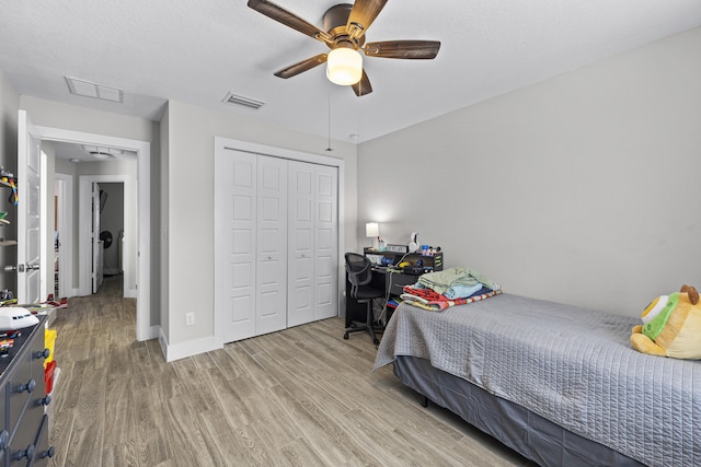 bedroom with ceiling fan, light hardwood / wood-style floors, a closet, and a textured ceiling