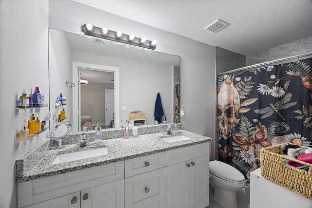 bathroom with a shower with curtain, vanity, a textured ceiling, and toilet