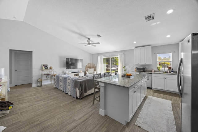 kitchen featuring a kitchen bar, white cabinetry, light hardwood / wood-style flooring, appliances with stainless steel finishes, and a kitchen island